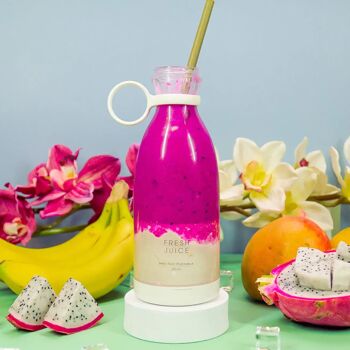 Ein weißer Fresh Juice Mixer gefüllt mit einem dunkellila Smoothie, umgeben von Bananen, Blumen und Drachenfrüchten.